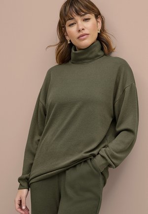 Olijfgroene coltrui gemaakt van zachte stof, met een comfortabele pasvorm en verlaagde schouders, gecombineerd met bijpassende broek voor een samenhangende look.