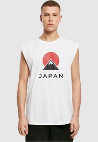 Weißes ärmelloses T-Shirt mit einem roten Sonnen- und schwarzen Bergmotiv sowie dem Wort "JAPAN" in fetten schwarzen Buchstaben bedruckt. Aus weichem Baumwollmaterial.