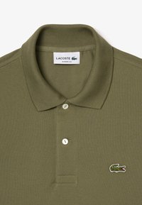 Olivgrön polo skjorta med klassisk passform, som har en ribbad krage, två vita knappar och en liten broderad krokodil-logotyp.