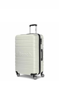 Hard-shell suitcase in matte white with black accents. Features a textured surface, a telescopic handle, and four spinner wheels for mobility.