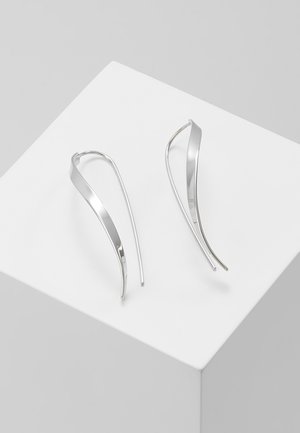 Silver earrings with a twisting, elongated design featuring smooth, reflective surfaces and a slim, minimalistic form.