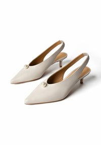 Escarpins slingback en cuir blanc à talons kitten avec bouts pointus et ornements décoratifs en perles sur fond blanc.