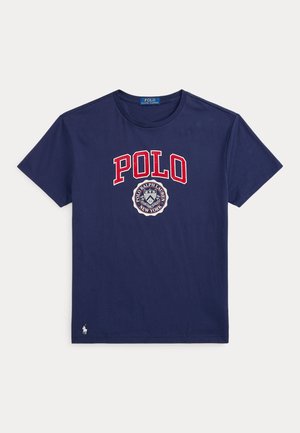 T-shirt bleu marine à manches courtes avec texte rouge "POLO" et logo circulaire Polo Ralph Lauren New York sur le devant, petit logo de cheval blanc près de l’ourlet.