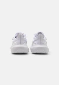 Baskets de sport blanches avec un dessus en maille texturée, semelle en caoutchouc lisse et talon rembourré. Design minimaliste avec un détail de logo discret.