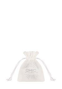 Witte stoffen trekkoordzak met een gedrukt zilveren logo, voorzien van stralen die van de merknaam uitgaan, een gladde textuur en een gerimpelde opening.