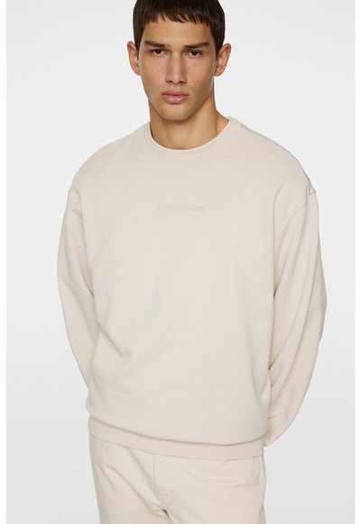 Beige sweatshirt lavet af blødt stof, med rund hals og sænkede skuldre, samt et diskret logodesign på fronten og ribbede manchetter.