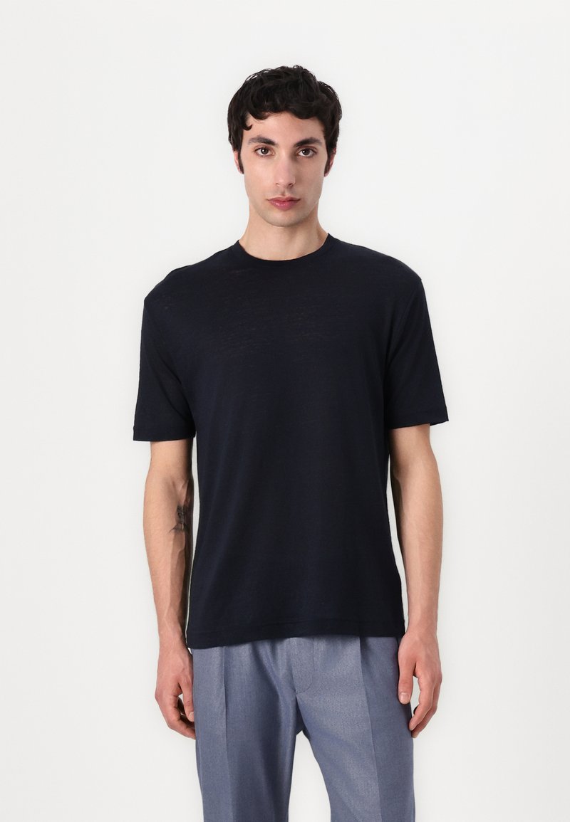 Marineblå kortermet crewneck t-skjorte laget av lett stoff, med en avslappet passform og glatt tekstur. Ingen synlige mønstre eller dekorasjoner.