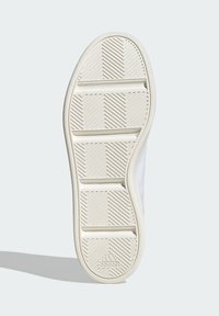 Bijela guma za tenisice s teksturiranom gumom. Sadrži dijagonalne i horizontalne utore za prianjanje te logo branda blizu pete.