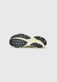 Shoe sole with a textured black rubber pattern, revealing a midsole in light cream. Features PUMAGRIP branding at the center.