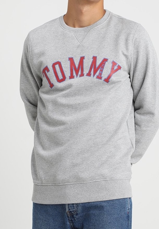 Sudadera gris de mezcla de algodón, que presenta un gran logo "TOMMY JEANS" en rojo y azul en el pecho, con un cuello y puños de ribete.