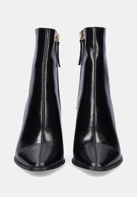 Botas de cuero negras hasta el tobillo con puntera en punta y un acabado suave. Presentan un cierre de cremallera lateral y una silueta vertical elegante.