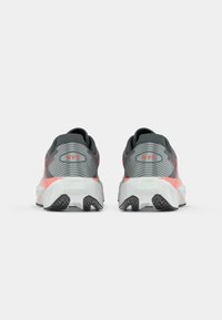 Gray athletic shoes with a textured upper, pink accents, and a white sole, featuring "NYC" printed on the back and a sturdy tread pattern.