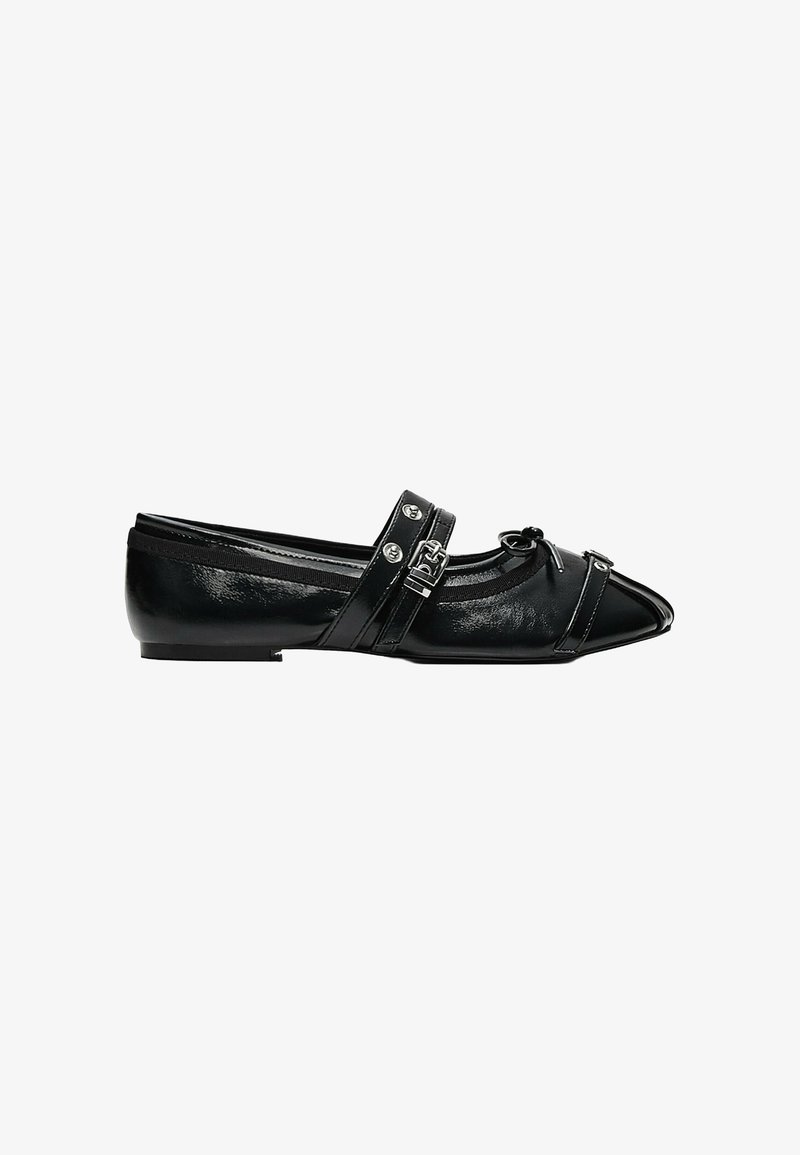 Chaussure plate en cuir verni noir avec bout pointu, brides décoratives à boucle et petit détail nœud sur fond blanc.