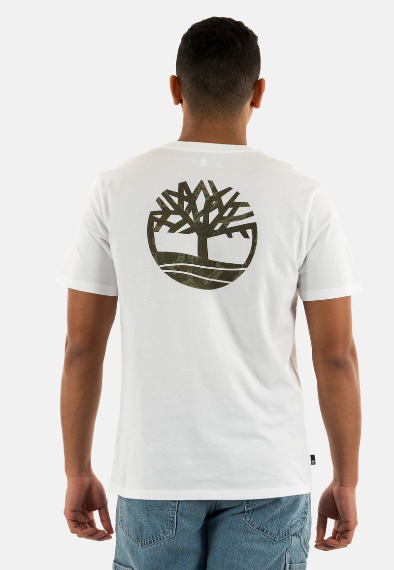 T-shirt blanc avec un grand logo d'arbre vert foncé dans le dos, complété par un design circulaire et une texture en coton douce.