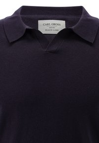 Dunkelviolettes Strickpolo mit V-Ausschnitt, kurzem Kragen und einem Etikett, das "CARL GROSS BLACK LINE" zeigt. Weiche Textur und minimale Details.