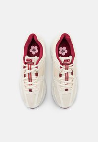 Nike Vomero 5 kengät kermavärisessä, jossa on viininpunaiset yksityiskohdat. Verkkomateriaali, pehmustettu sisustus, valkoiset nauhat, jossa on kukkakuvioinen sisäpohja.