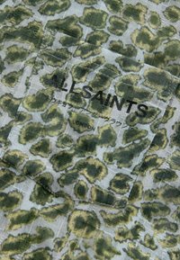 Tessuto con stampa leopardata verde, caratterizzato da una superficie texturizzata, con un'etichetta del marchio "ALLSAINTS" integrata nel design.