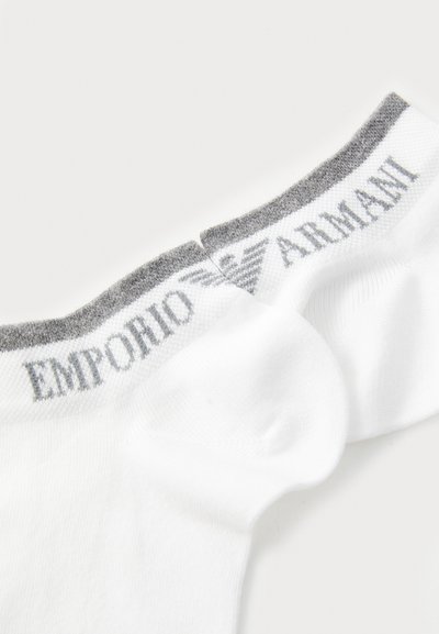 Chaussettes blanches avec une bande grise en haut portant "EMPORIO ARMANI" et un logo. Fabriquées en tissu doux et respirant avec une texture lisse.