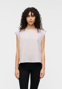 Ανοιχτό ροζ τοπ με κοντά μανίκια από απαλό ύφασμα, με στρογγυλή λαιμόκοψη και άνετη εφαρμογή, συνδυασμένο με μαύρο, εφαρμοστό παντελόνι.