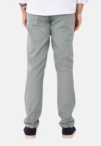 Pantaloni in cotone grigio chiaro con vestibilità dritta, cuciture visibili e vita regolare, abbinati a scarpe casual scure.