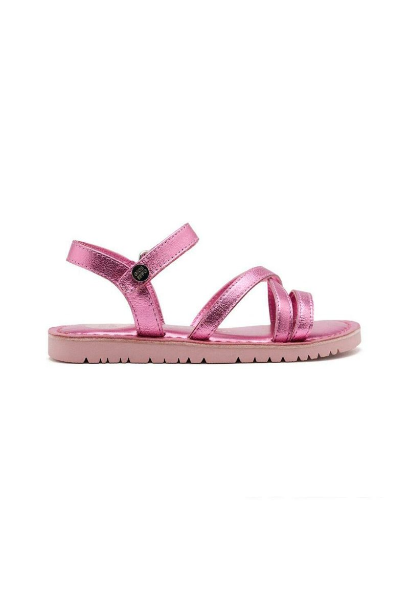 Sandalias metálicas rosas con tiras entrecruzadas y hebilla. Suela plana con un dibujo pronunciado. Textura suave y diseño minimalista.