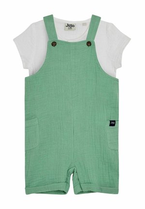 Mono de algodón verde con un acabado texturizado, que presenta tirantes ajustables, dos bolsillos y una camiseta blanca de manga corta debajo.