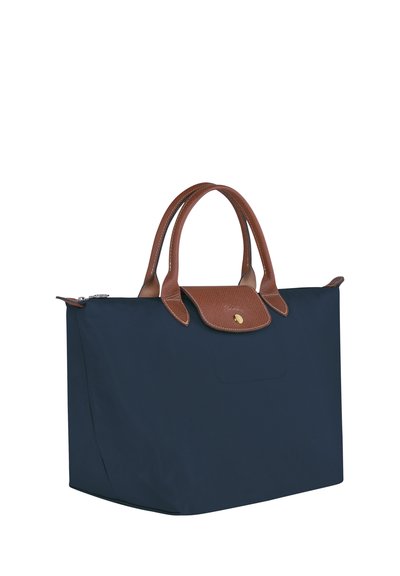 Navy blue nylon tote bag with brown leather handles and flap. Features a gold logo accent and a zip closure. Smooth texture, rectangular shape.