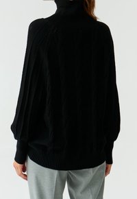 Pull en maille noir avec un col haut, motif en torsades et ourlet côtelé. Présente des épaules tombantes et une coupe ample et décontractée.