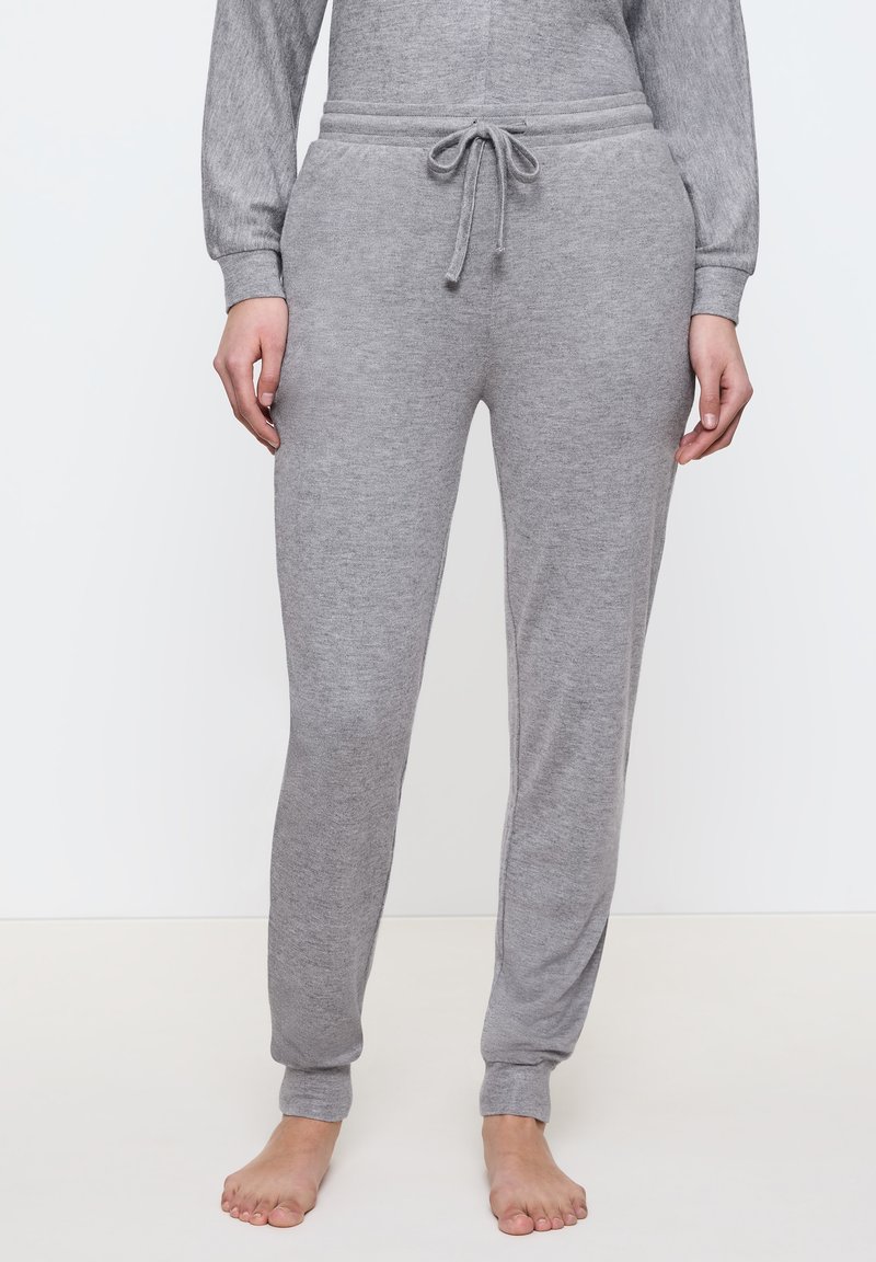 Grijze sweatpants hebben een drawstring tailleband, taps toelopende benen en een zachte textuur. Ze zijn aangesloten bij de enkels met ribgebreide boorden.