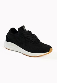 Black athletic shoe with a knitted upper, flat black laces, and a white midsole. Features a textured design and gum rubber outsole.