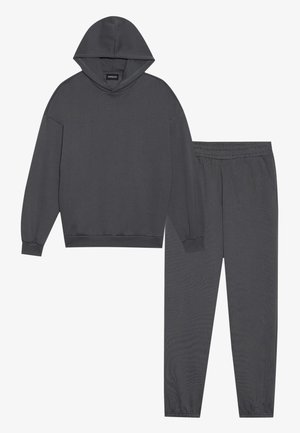 Sudadera con capucha gris oscuro con hombros caídos y pantalones de chándal a juego que cuentan con una cintura elástica y piernas ajustadas.