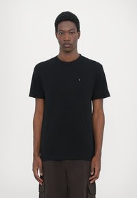 Tricou negru cu guler rotund din bumbac, cu mâneci scurte, având un mic accent argintiu pe piept. Design simplu, clasic.