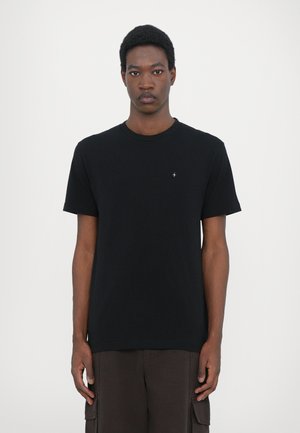 Schwarzes Rundhals-T-Shirt aus Baumwolle mit kurzen Ärmeln, das einen kleinen silbernen Akzent auf der Brust hat. Einfaches, klassisches Design.