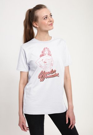Hvid bomulds t-shirt med et pink grafik af Wonder Woman og stiliseret tekst "Wonder Woman" i en fed, retro skrifttype. Korte ærmer og rund hals.