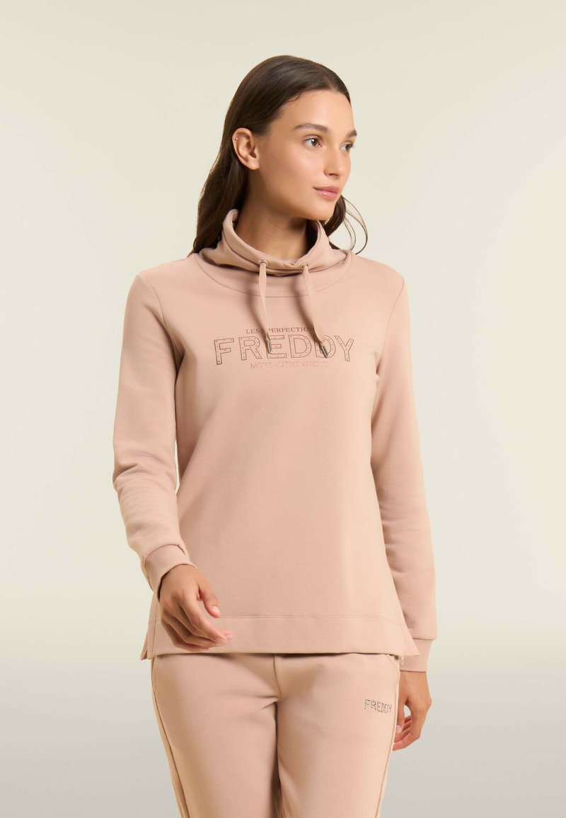 Sweatshirt à capuche rose clair en tissu doux avec une coupe décontractée, doté d'un cordon de serrage et d'un texte de marque en couleur contrastante.