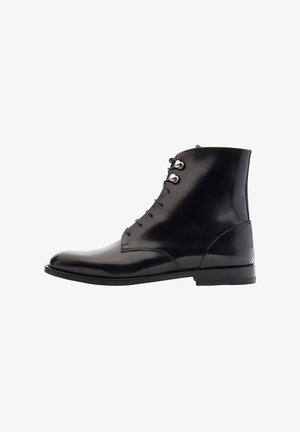Zwarte leren enkelboots met een glanzende afwerking, voorzien van een slank ontwerp, ronde neus en een scheef veterafsluiting met metalen oogjes.