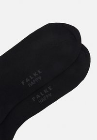 Sorte sokker laget av mykt materiale, med merkevarenavnet "FALKE" og ordet "HAPPY" i grå tekst, med en glatt tekstur og avrundede tær.