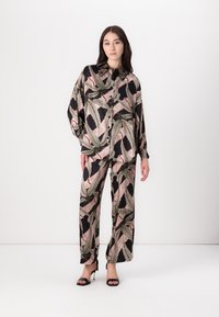 Blusa nera e rosa con motivo a stampa e maniche oversize abbinata a pantaloni a gamba larga. Tessuto morbido con motivi a foglia e accenti a contrasto.