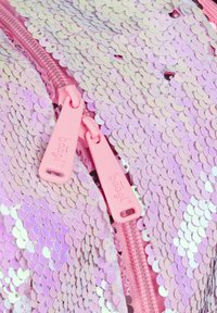 Zaino rosa in paillettes con una texture scintillante, dotato di una cerniera rosa abbinata e tiranti, che mostra una superficie vibrante e iridescente.