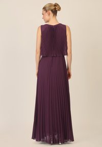 Violetti laskostettu mekko, jossa on hihaton muotoilu, kerroksellinen yläosa ja lattiaa hipova hame. Varustettu takana olevalla vetoketjulla ja pehmeällä, valuvalle rakenteelle.