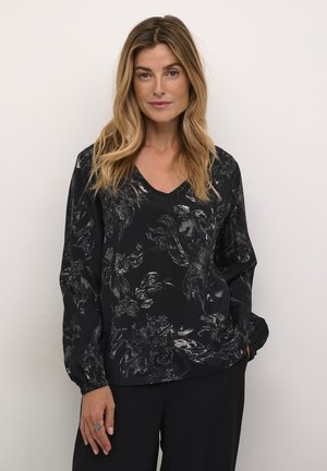 Schwarze Bluse mit V-Ausschnitt, floralen Mustern in Grau, lockerer Schnitt und langen Ärmeln mit elastischen Bündchen. Der Stoff wirkt weich und strukturiert.