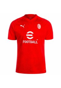 Maglietta da calcio rossa con maniche corte, scollatura a V, motivo triangolare, dettagli del logo bianchi e testo "FOOTBALL" sul davanti. Il produttore è Puma.