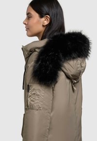 Khaki parka jakk, millel on must faux karusnahast kapuuts, lukustatav tasku varrukal ja viimistlus, mis näeb välja sile ja vastupidav.