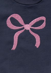 Navy sweatshirt featuring a large pink glitter bow design at the center, with a textured finish and smooth fabric.