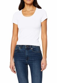 T-shirt blanc à manches courtes avec un col rond, design ajusté, en tissu lisse, associé à un jean slim-fit bleu foncé.