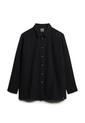 Camisa negra de manga larga hecha de tejido texturizado, con cierre de botones en la parte delantera, cuello clásico y un bolsillo en el pecho.
