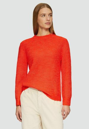 Helle orange gestrickte Pullover mit strukturiertem Muster, rundem Ausschnitt und langen Ärmeln. Kombiniert mit hellen Hosen.