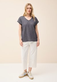Top corto de manga corta azul oscuro texturizado con escote en V, combinado con pantalones de pierna ancha blancos y zapatillas ligeras con detalles en azul.