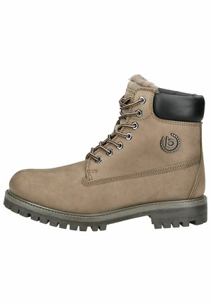 Bota de cuero marrón claro con un cuello acolchado negro, ojales de metal y suela de goma duradera con dibujos profundos para tracción.