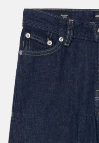 Slittede mørkeblå denimjeans med avslappet passform, sølvdetaljer, fem lommer og kontraststing langs sømmene for ekstra detalj.